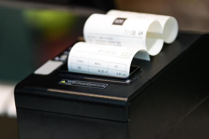 Thermal receipt printer outputting a paper receipt with itemized purchase totals