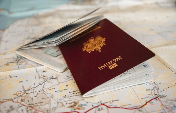 Two passports, one open and one closed, resting on a geographic map