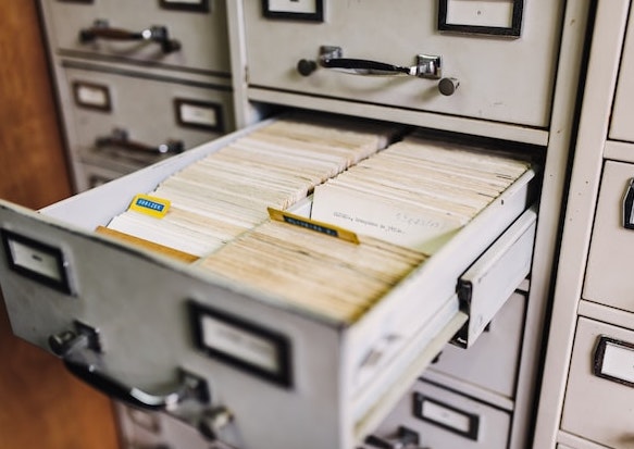 Open filing cabinet drawer filled with indexed paper cards representing analog data storage