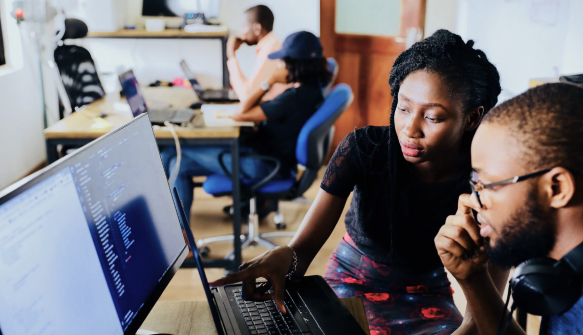 Two developers collaborating at a laptop analyzing code in a modern office