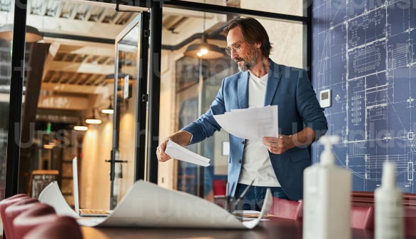 Business professional reviewing paper documents next to a laptop in an office