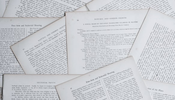 Multiple printed text document pages scattered and overlapping on a white surface