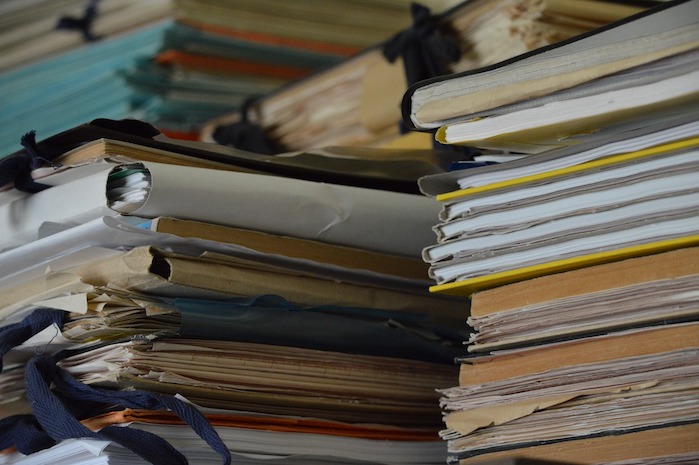 Large stacks of physical paper documents and folders representing unstructured data
