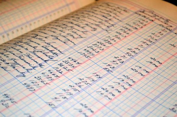 Open handwritten accounting ledger with rows of manual numerical entries