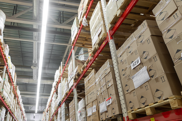 Large warehouse with tall red shelving units stacked with cardboard boxes on pallets