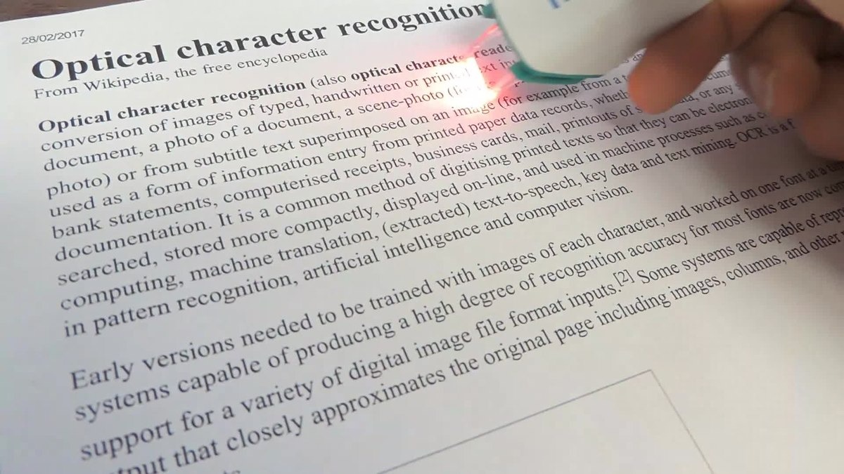Handheld OCR scanner with red laser reading a printed document about optical character recognition